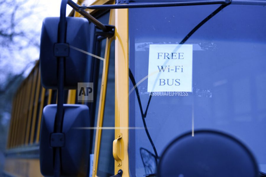In this Thursday, March 26, 2020, photo, this wi-fi-enabled school bus, seen at an apartment complex in Winnsboro, S.C., is one of many being sent to rural and lower-income areas around South Carolina to help students with distance learning during the new coronavirus outbreak. With routers mounted inside, the buses broadcast enough bandwidth in an area the size of a small parking for parents to drive up and children to access the internet from inside their cars. (AP Photo/Meg Kinnard)