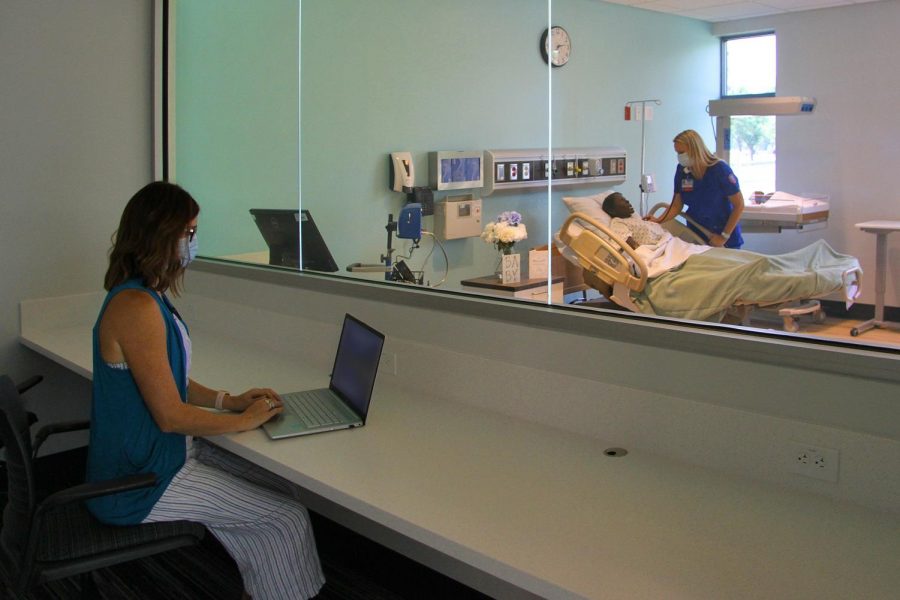 A teacher sits behind a one-way mirror while monitoring the students as they work.